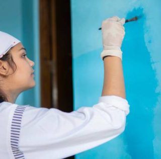 istockphoto-1270405142-612x612 Indian Young girl painting wall with blue paint and making design through paint brush. Home renovation.